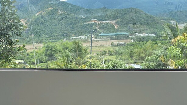 A room with a view of a mountainous landscape, a tatami mat floor, and four cushions in different colors.
