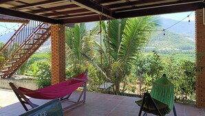 A covered outdoor area with a hammock, a swing, and a view of a mountainous landscape.