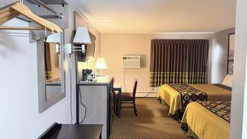 A hotel room with a desk, chair, bed, and a window with curtains.