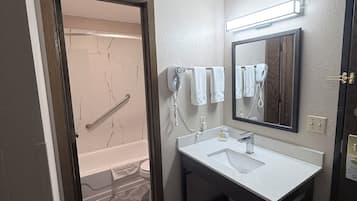 A bathroom with a bathtub, a sink, and a mirror.