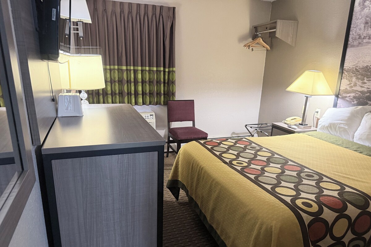 A hotel room with a desk, chair, bed, and a view of a waterfall.