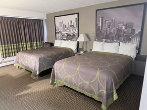 A hotel room with two beds, a window with curtains, a lamp, and two framed cityscape pictures on the wall. - Villa inn (Owatonna)
