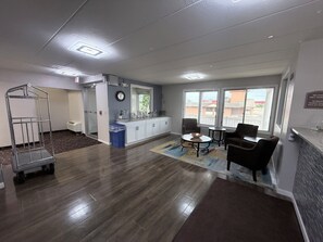 A hotel lobby with a reception desk, seating area, and a kitchenette. - Villa inn (Owatonna)