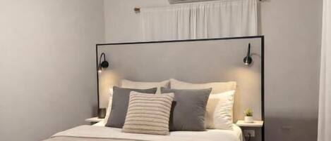 Een slaapkamer met een houten plafond, een bed met hoofdeinde, nachtlampjes en een airconditioning.