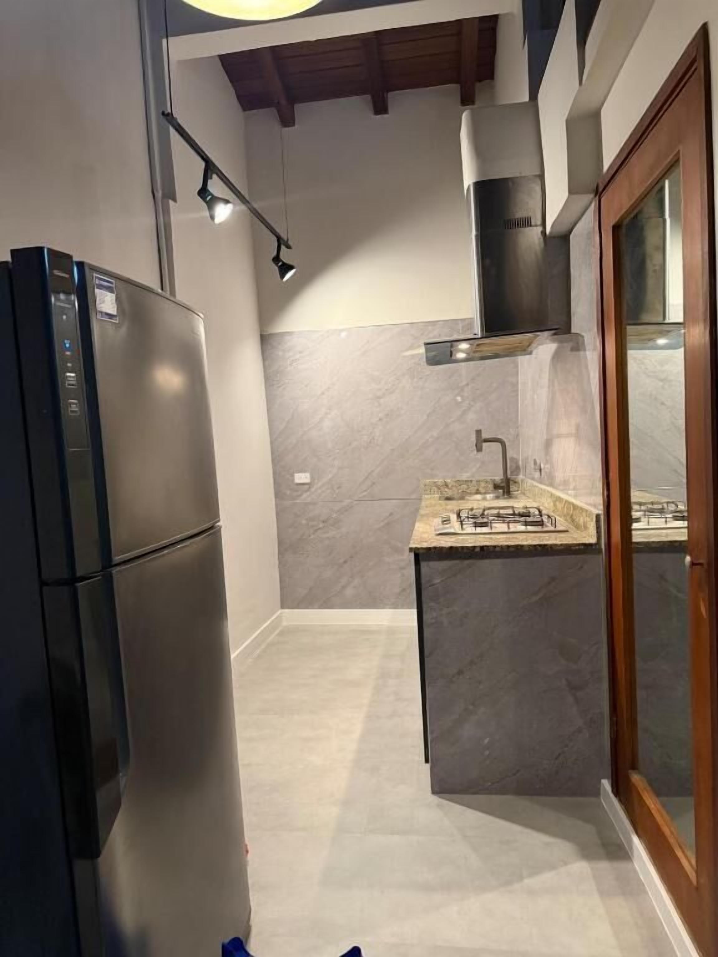 Eine kleine Küche mit einem Einbaukühlschrank, einem Gasherd und einem Holzschrank.