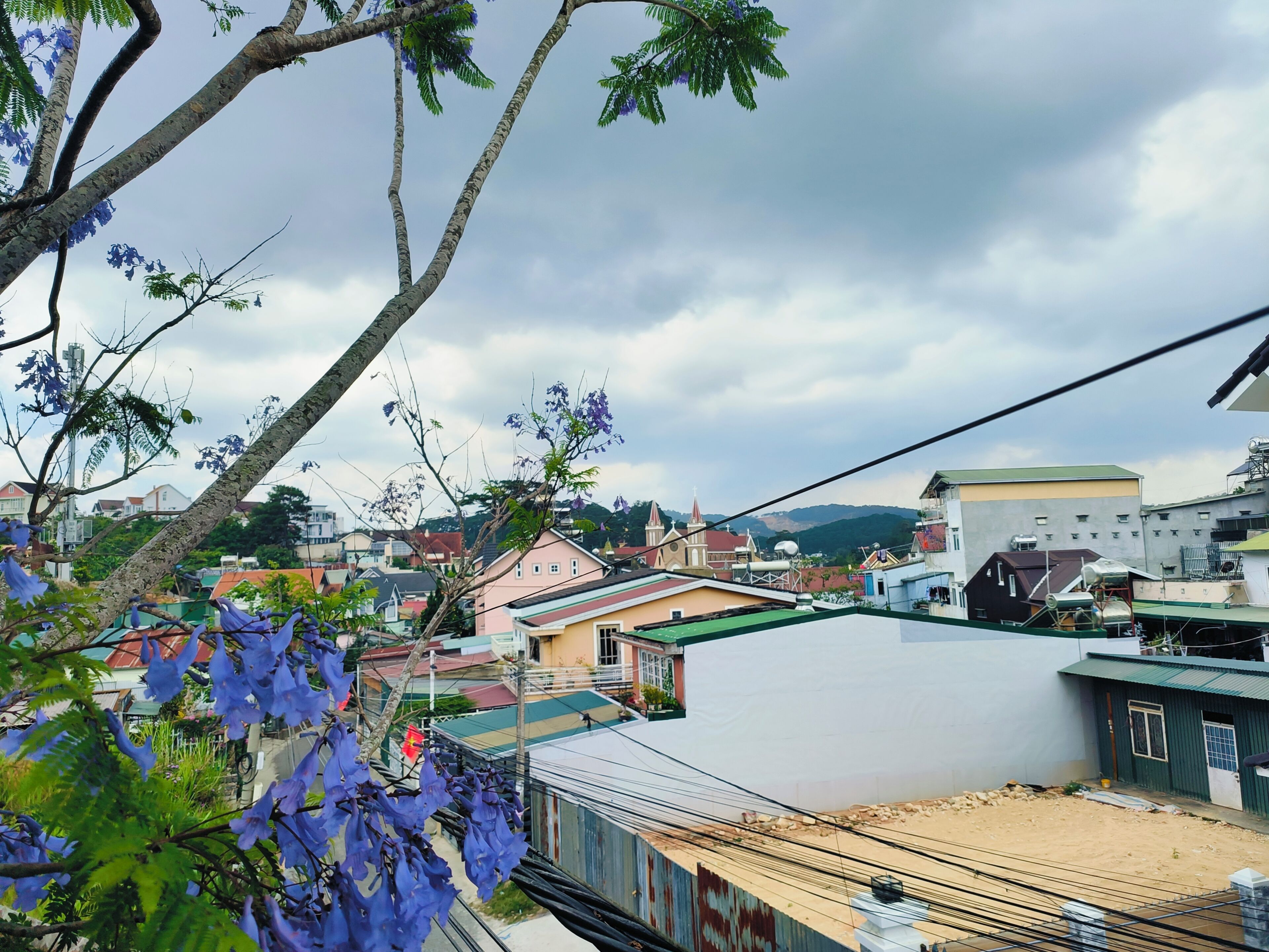 A residential area with houses, a church, and a hill in the background.