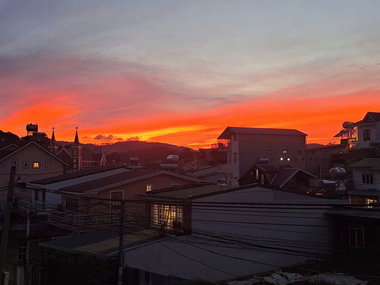 Asuinalue, jossa on taloja ja kirkko, auringonlaskun värittämän taivaan alla.