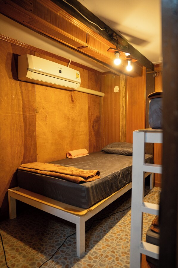 A compact room with a single bed, a small table, and a wall-mounted heater.