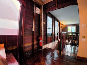 A wooden interior with a fire extinguisher, a staircase, and a window with a view.