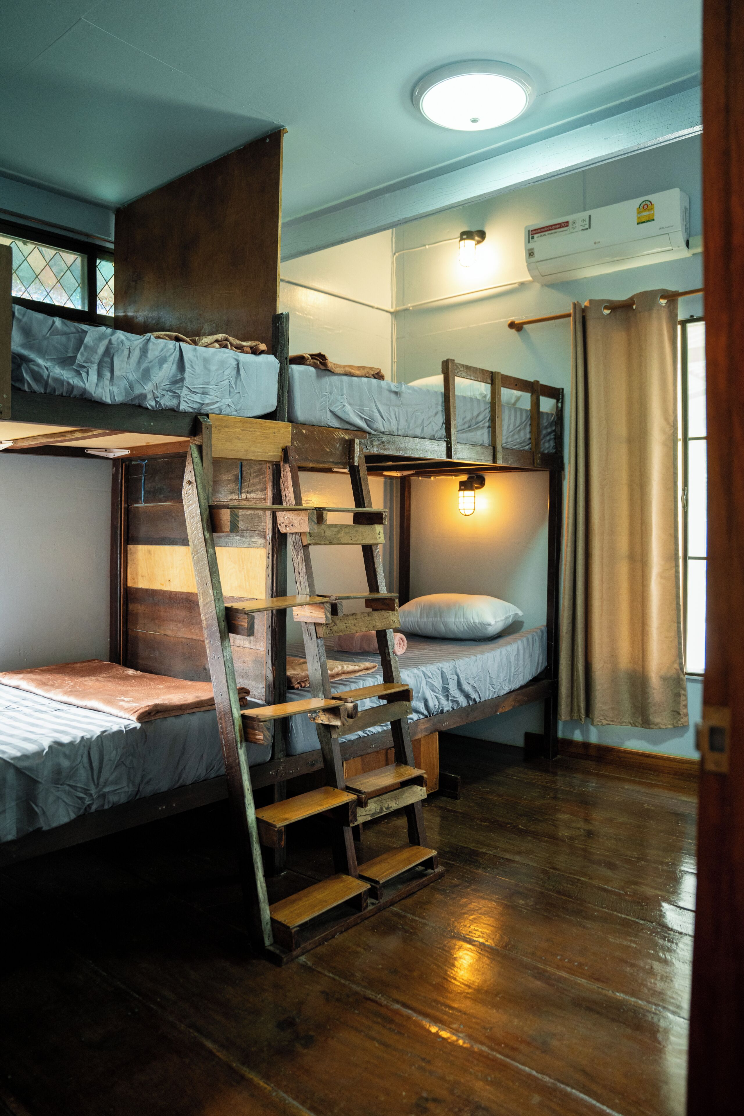 A bunk bed room with a ladder, a window, and an air conditioning unit.