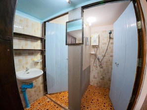A bathroom with a sink, a shower, and tiled walls.