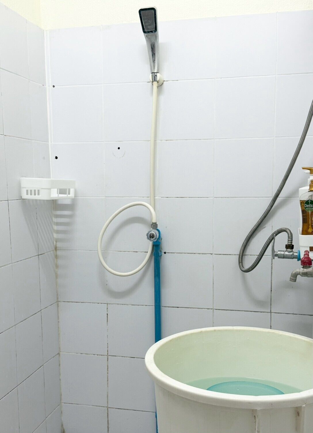 A bathroom with a shower, a basin, and a bottle of Dettol soap.