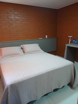 A bedroom with a bed, pillows, a radiator, and a small table with a box on it. - Vacation home with 2 bedrooms and pool - Caldas Novas (Caldas Novas)