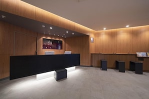 A reception area with a wooden panel wall, a reception desk, and a tiled floor. - R B Hotel Sendai East (Sendai)