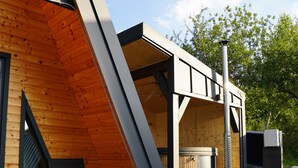 A modern building with a sloped roof, a wooden exterior, and a metal staircase leading to a door.