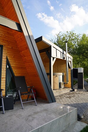 A modern building with a sloped roof, a wooden exterior, and a metal staircase leading to a door.