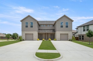 A two-story residential building with a symmetrical facade, a central entrance, and a driveway leading to the garage. - Super Spacious 6-bedroom Newly Built Home in Denton (Denton)