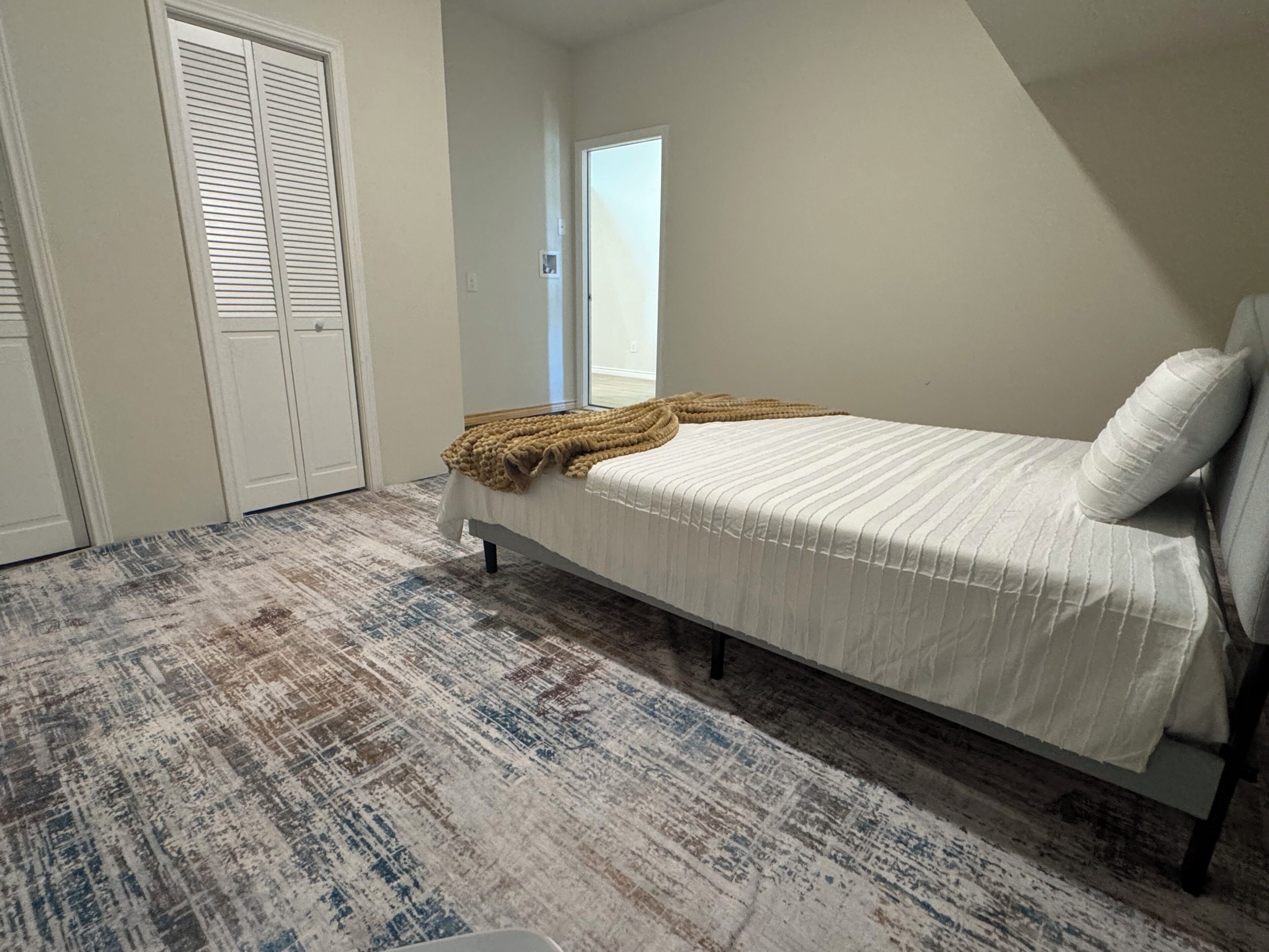 Un dormitorio con cama, ventana y puerta.
