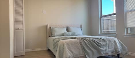 Ein Schlafzimmer mit Bett, Fenster und Tür.