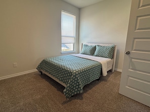 A bedroom with a bed, a window, and a door. - Super Spacious 6-bedroom Newly Built Home in Denton (Denton)