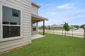 A residential building with a covered porch, a well-maintained lawn, and a metal fence. - Super Spacious 6-bedroom Newly Built Home in Denton (Denton)