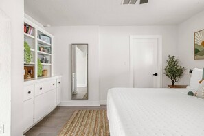 A bedroom with a bed, a dresser, a mirror, and a door. - Palmera Haus: Scottsdale Home, Pool & King Suites (Scottsdale)