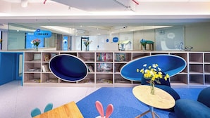 Uma biblioteca moderna com estantes, uma área de estar azul e um letreiro com a inscrição 'Hi LIBRARY'.