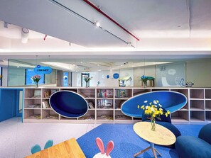 Eine moderne Bibliothek mit Bücherregalen, einer blauen Sitzgruppe und einem Schild mit der Aufschrift 'Hi LIBRARY'.