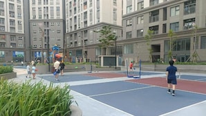 Uma quadra de esportes ao ar livre com várias quadras de tênis, cercada por edifícios residenciais.
