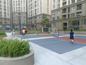 Ein Sportplatz im Freien mit mehreren Tennisplätzen, umgeben von Wohngebäuden.