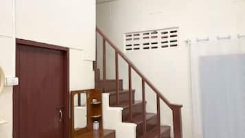 A staircase with wooden steps and a handrail, a brown door, and a white wall with a small window.
