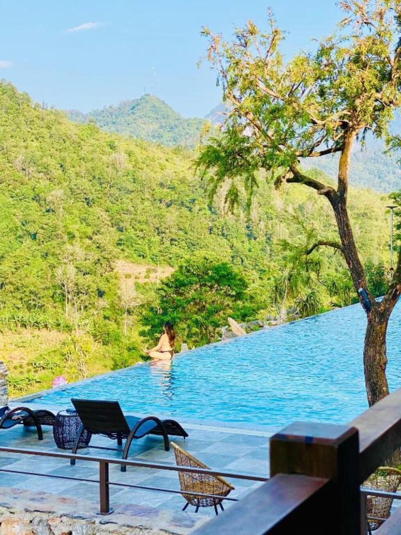 A poolside area with lounge chairs and a view of a mountainous landscape.