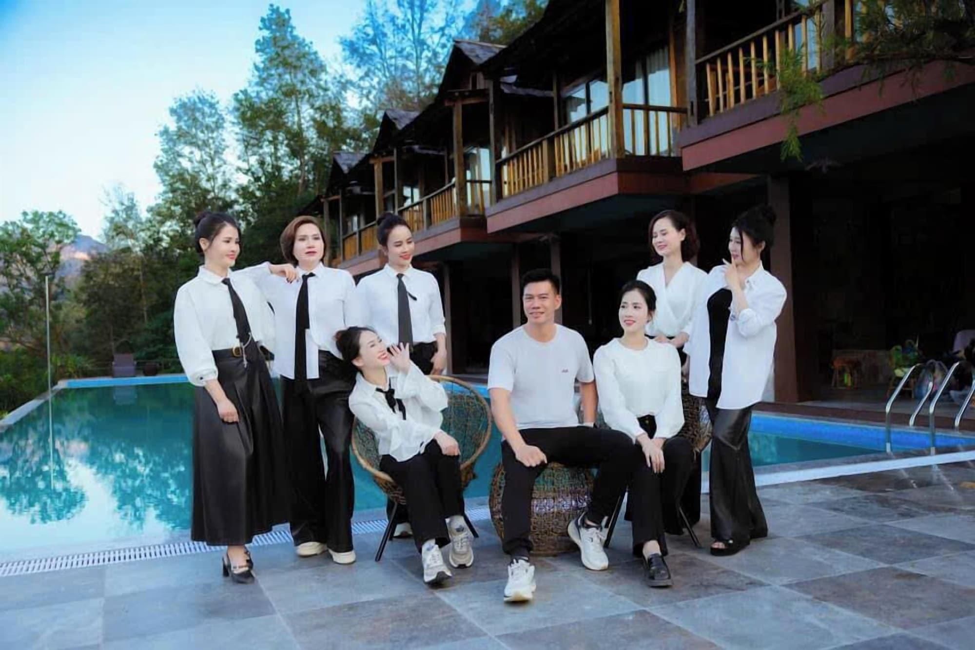 Un grupo de personas posando frente a un edificio con piscina.