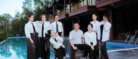 A group of people posing in front of a building with a pool.