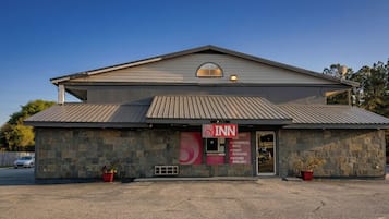 A 2-story building with a stone facade, a red sign indicating it's an 8th Inn, and a clear sky.