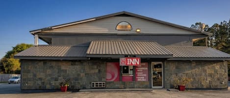 A 2-story building with a stone facade, a red sign indicating it's an 8th Inn, and a clear sky.