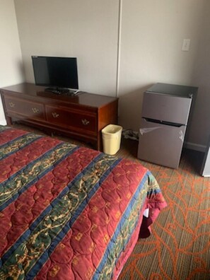 A hotel room with a bed, a television, a refrigerator, and a waste bin. - 8 Inn (Americus)