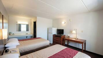 A hotel room with two beds, a desk, a television, and a mirror.