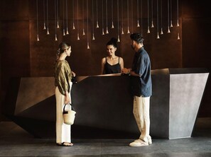 Un espace d’accueil au design moderne, comprenant un comptoir de réception et des luminaires suspendus.