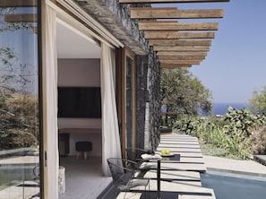 Un área de estar al aire libre con una mesa y sillas, un muro de piedra y vistas al mar.