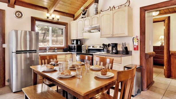 Una cocina con armarios de madera, un refrigerador de acero inoxidable, una estufa y una mesa de comedor con platos y vasos.
