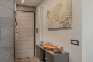 A hallway with a wooden door, a coat rack with keys, a framed artwork, and a console table with a decorative object. - AffittiPontediLegno - Fumeclo (Temù)