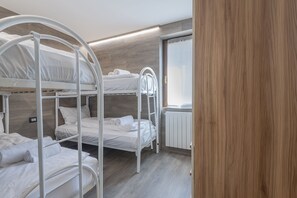 A room with bunk beds, a wooden floor, and a window with curtains. - AffittiPontediLegno - Fumeclo (Temù)