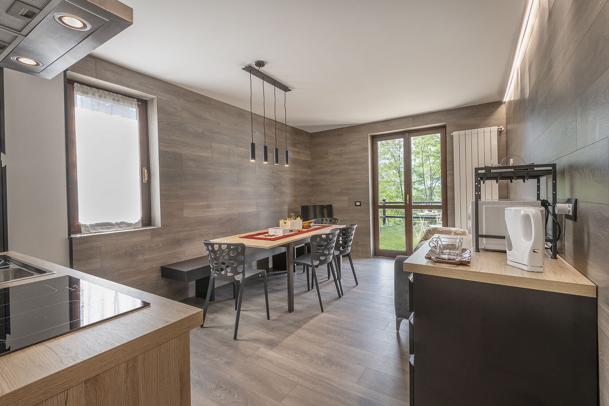 Una cocina moderna con zona de comedor, suelo de madera y un ventanal grande.
