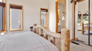 Un dormitorio con una cama grande, cabecero de madera y vistas por una ventana.