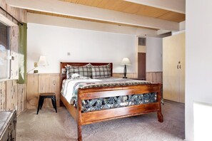A bedroom with a wooden bed, two bedside lamps, a wooden wardrobe, and a window with curtains. - Bear Mountain Views #2235 (Big Bear Lake)
