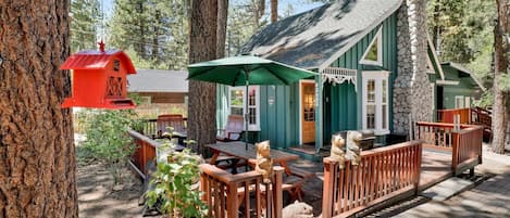 A cabin with a porch, outdoor seating, and a stone chimney.