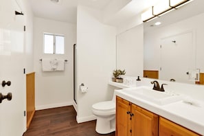 Ein Badezimmer mit Toilette, Holzwaschtisch, großem Spiegel und Fenster.
