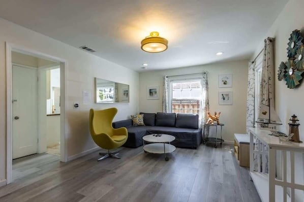 A modern living room with a sofa, a yellow chair, a round coffee table, and a ceiling light fixture. - Marbella Lane Convenient Home In Sunnyvale (Sunnyvale)