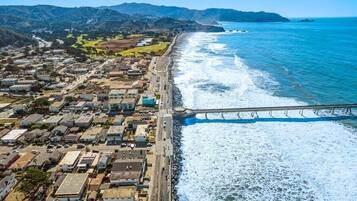 An aerial view of a coastal town with a bridge connecting the land to the beach.